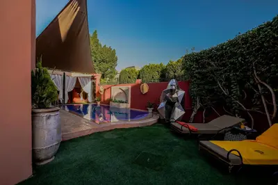 a backyard with a lawn with a tent and a pool at Riad dar Nafaa in Marrakech