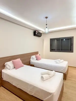 a room with two beds and a tv on the wall at Menara Prestige Duplex 4BR with Pool Access in Marrakech