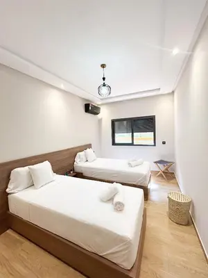 a hotel room with two beds and a television at Menara Prestige Duplex 4BR with Pool Access in Marrakech
