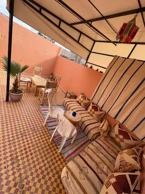 a patio with a couch and chairs under an umbrella at Dar El Bahja à 5 minutes de la place Jemaa el-Fna in Marrakech