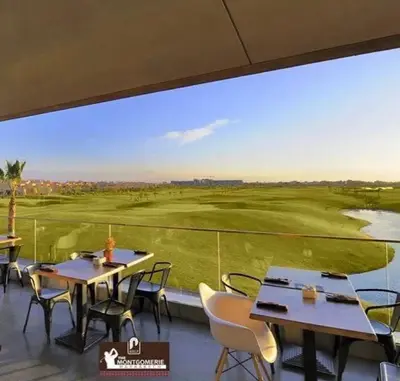a view of a golf course from a restaurant with tables and chairs at Chez fatina in Marrakech