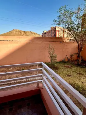 a white fence next to a wall with a building at Studio Cosy Proximité Confort in Marrakech