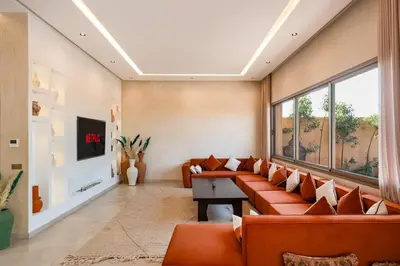 a living room with orange couches and a tv at Villa Nabil by TheCasaEdition Cinema, Heated pool & Jaccuzi in Marrakech