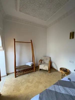 a bedroom with a bed and a chair at Riad Amanar in Marrakech