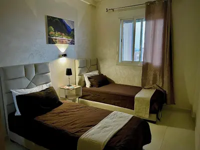 a hotel room with two beds and a window at Cosy appartement near to airport in Marrakech