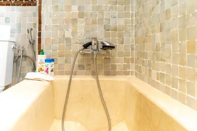 a bath tub with a shower in a bathroom at Villa riad raffinée privée à Marrakech in Marrakech