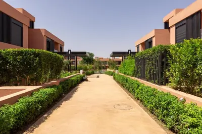 a walkway between two buildings with bushes at Élégance et confort 3 chambre sur le golf de Noria in Marrakech