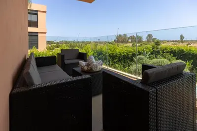 a balcony with wicker furniture and a view of a field at Élégance et confort 3 chambre sur le golf de Noria in Marrakech