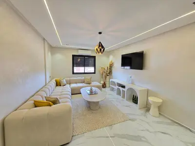 a living room with a couch and a tv at Appartement avec piscine in Marrakech