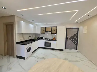 a kitchen with white cabinets and a washer and dryer at Appartement avec piscine in Marrakech