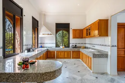 a kitchen with wooden cabinets and a marble counter top at Taj Palmeraie Palace Marrakech in Marrakech