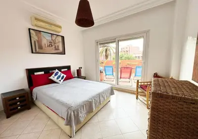 a bedroom with a bed and a balcony with chairs at Escapade citadine avec balcon et confort total in Marrakech