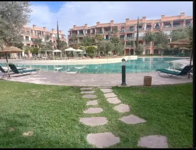 a large swimming pool with a large building in the background at Appartement cosy moderne luxe in Marrakech