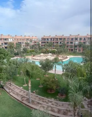 a resort with a pool and palm trees and buildings at Appartement cosy moderne luxe in Marrakech