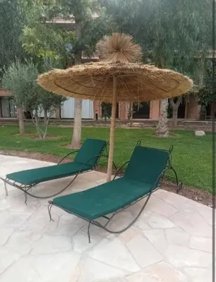 two green chairs and an umbrella on a patio at Appartement cosy moderne luxe in Marrakech