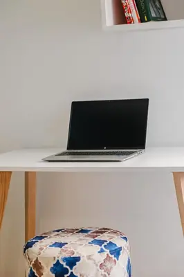 a laptop computer sitting on a white desk with a stool at Appartement Relax & Confort au Cœur de Marrakech in Marrakech