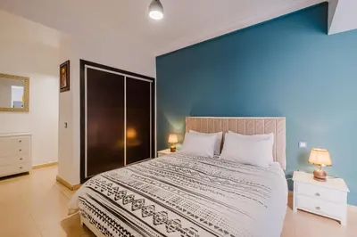 a bedroom with a large bed with a blue wall at Appartement Relax & Confort au Cœur de Marrakech in Marrakech