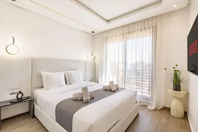 a white bedroom with a large bed and a large window at Sakina Appartement Luxe Gueliz in Marrakech