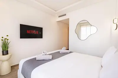 a bedroom with a white bed and a tv at Sakina Appartement Luxe Gueliz in Marrakech