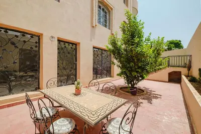 a patio with a table and chairs and a tree at Very comfortable villa in the heart of Marrakech in Marrakech