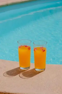two glasses of orange juice sitting next to a pool at Very comfortable villa in the heart of Marrakech in Marrakech