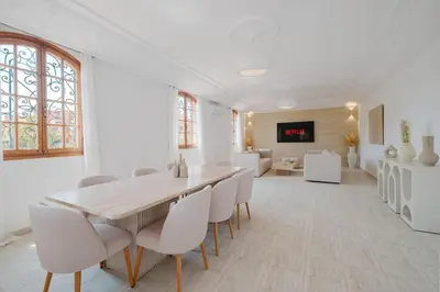a white dining room with a wooden table and white chairs at Very comfortable villa in the heart of Marrakech in Marrakech