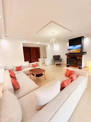 a living room with white furniture and a flat screen tv at Villa privée in Marrakech