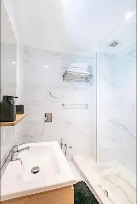 a white bathroom with a sink and a shower at Charme Central Appart Gueliz en Face La gare in Marrakech
