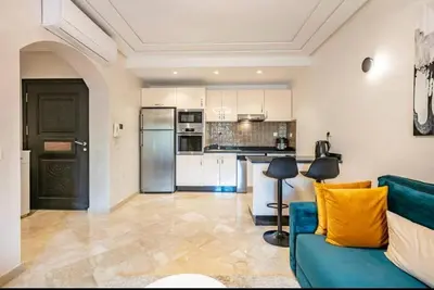 a living room with a blue couch and a kitchen at Charme Central Appart Gueliz en Face La gare in Marrakech