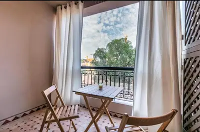 a table and two chairs in front of a window at Charme Central Appart Gueliz en Face La gare in Marrakech
