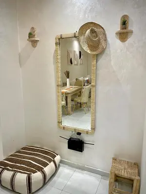 a mirror in a room with a table and a chair at Appartement cosy 2 min aéroport Marrakech 2 chambres bien équipé in Marrakech