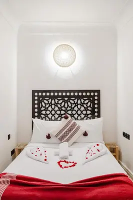 a bed with white sheets and a red blanket at Riad - Jacuzzi & Breakfast , 5min walk Jemaa El Fnaa & Vue Rooftop Médina in Marrakech