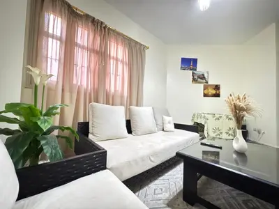 a living room with a white couch and a table at Only 5-minutes walk to airport, your perfect choice for an early or late flight in Oulad Akkou