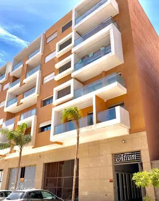 an apartment building with a palm tree in front of it at Lovely 2 bedroom apartment in Marrakech