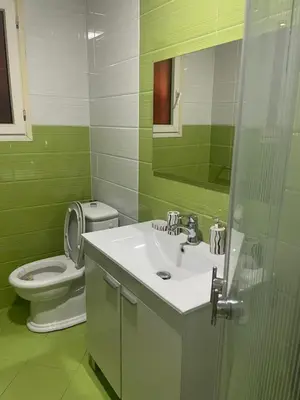 a green bathroom with a sink and a toilet at Duplex Village in Marrakech