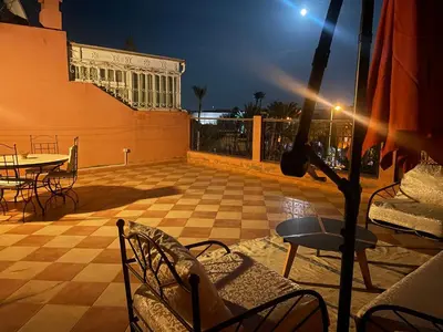 a patio at night with a table and chairs at Duplex Village in Marrakech