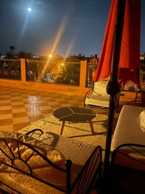 an umbrella and chairs on a balcony at night at Duplex Village in Marrakech