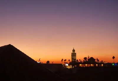a sunset with a clock tower and a building at amazing home and amazing rooftop in Marrakech