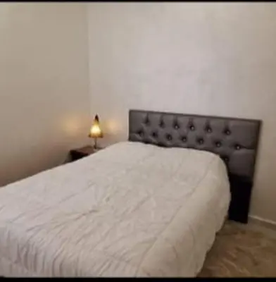 a bedroom with a bed with a white blanket and a lamp at Appartement avec bel vue au centre de Marrakech in Marrakech