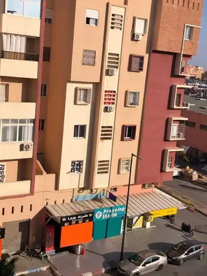 a tall building with cars parked in front of it at Appartement avec bel vue au centre de Marrakech in Marrakech