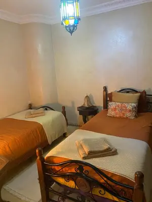 a bedroom with two beds and a chandelier at Le Riad l'étoile beldi in Marrakech