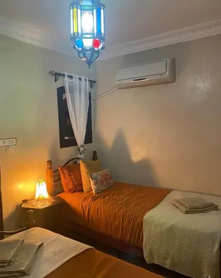 a bedroom with two beds and a light and a lamp at Le Riad l'étoile beldi in Marrakech