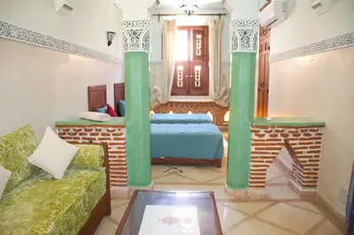a room with a bed with green columns and a couch at Riad-style villa with a private pool in Marrakech