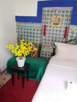 a room with a bed and a table with yellow flowers at Riad Dar Medina Land in Marrakech