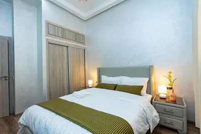 a bedroom with a large bed with a green and white blanket at Elegant and Modern Apartment, Calm Cosy and Central in Marrakech