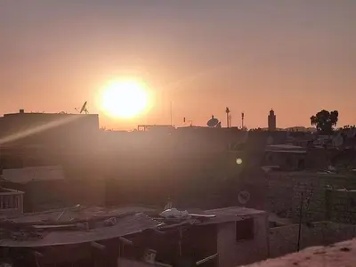 a sunset over a city with the sun in the sky at Riad EL BADIS in Marrakech