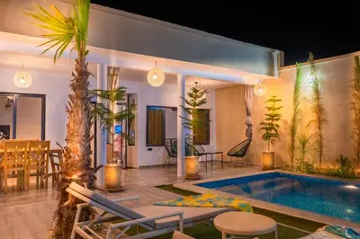 a living room with a swimming pool and palm trees at Villa loujain in Marrakech