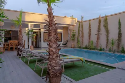 a palm tree next to a house with a swimming pool at Villa loujain in Marrakech