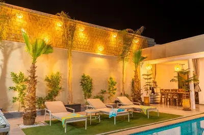a patio with chairs and a pool at night at Villa loujain in Marrakech