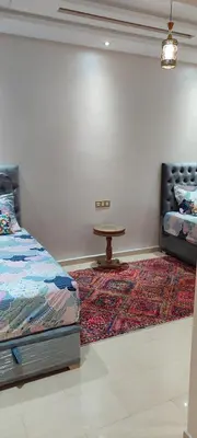 a bedroom with a bed and a table on a rug at Dar lala soukaina in Marrakech